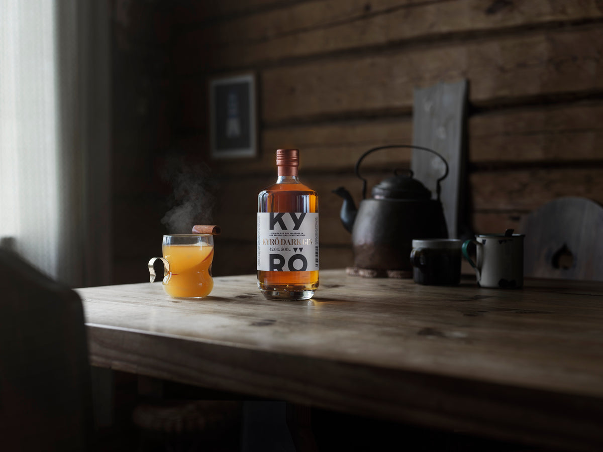 Kyrö Dark Gin ja kuuma omenamehudrinkki mökin pöydällä